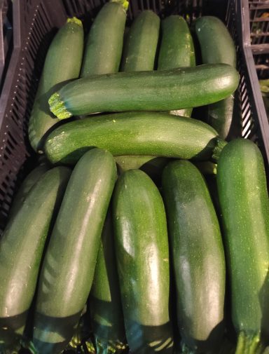 Calabacines verdes frescos apilados en una cesta.