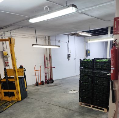 Almacén con estantes de cajas y equipo de carga en un espacio iluminado.