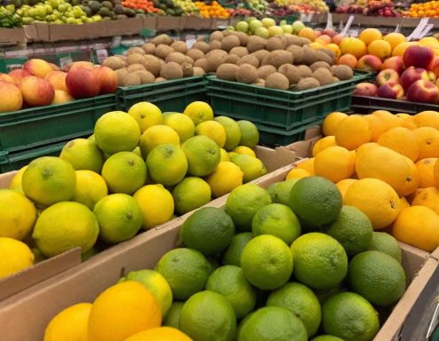 Variedad de cítricos y frutas en cajas, incluyendo limones y limas.